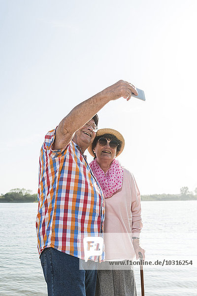 Senior couple taking a selfie at riverside