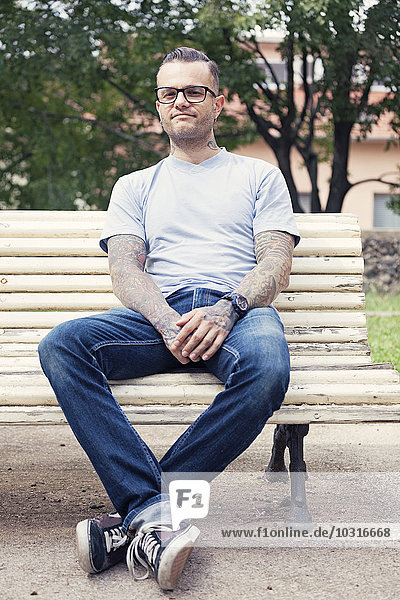 Tattooed man sitting on a park bench