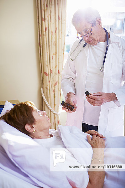 Arzt im Gespräch mit Seniorin im Krankenhausbett liegend