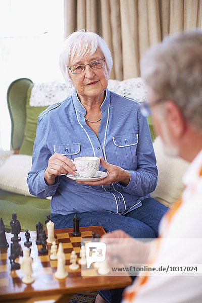 Senior couple playing chess and drinking coffee