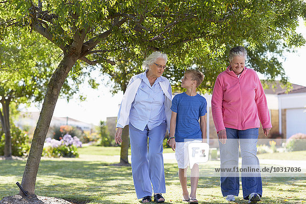 Zwei ältere Frauen  die mit einem Jungen im Park spazieren gehen.