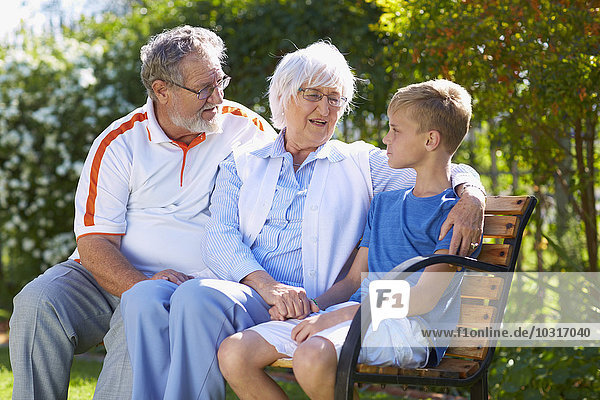 Großeltern und Enkel auf der Parkbank sitzend