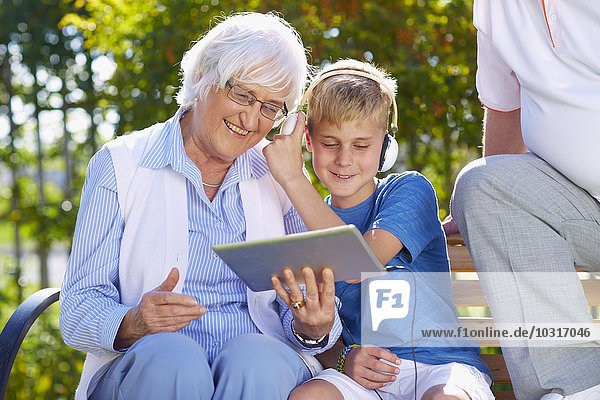 Enkel und Großeltern mit digitalem Tablett im Park