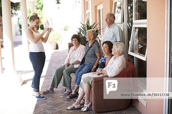 Young woman taking picture of senior people in a retirement village