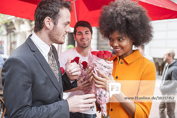 Mann kauft rote Rosen für eine Frau
