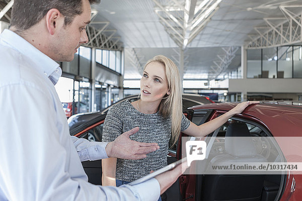 Autohändlerin erklärt der jungen Frau das neue Auto