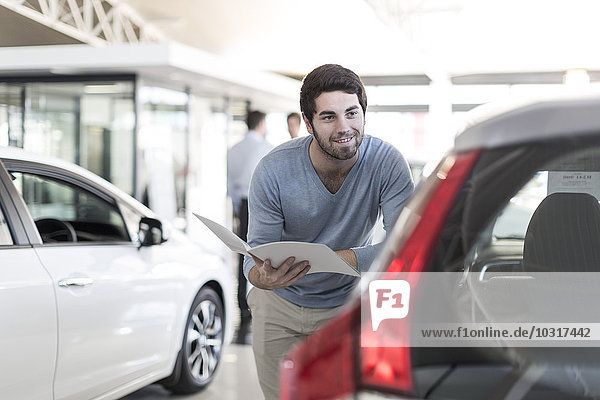 Smiling man looking at new car at car dealership