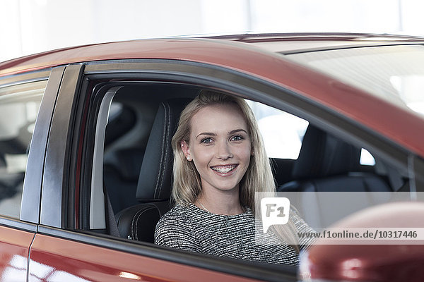 Smiling young woman sitting in new car