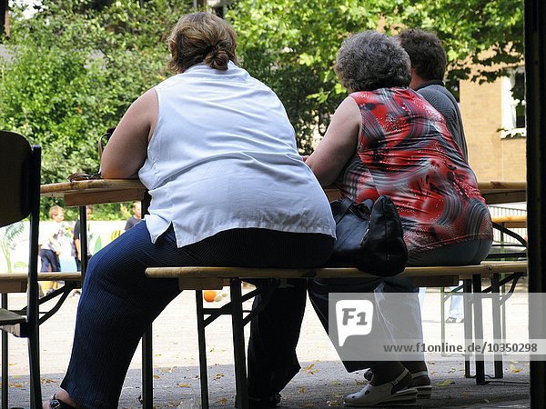 zwei übergewichtige Frauen sitzen an einem Tisch in der Natur