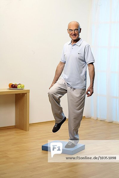 Älterer Mann macht Gymnastik auf instabiler Unterlage - Basis - Gleichgewicht - Senior - Kombination - Heben von Knie und Bein zur Seite