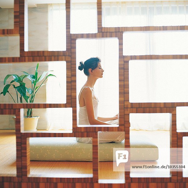 Side profile of a young woman meditating in a room