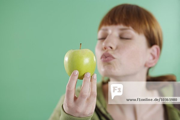 Frau bläst Kuss auf Apfel