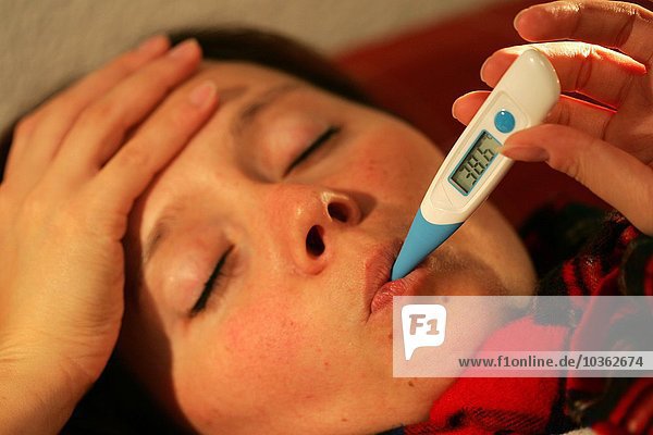 Gesundheit  Kälte  Krankheit. Junge Frau misst ihre Blutwärme mit einem Fieberthermometer