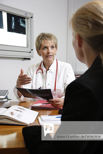 Ärztin in einem Krankenhaus spricht mit einem Patienten
