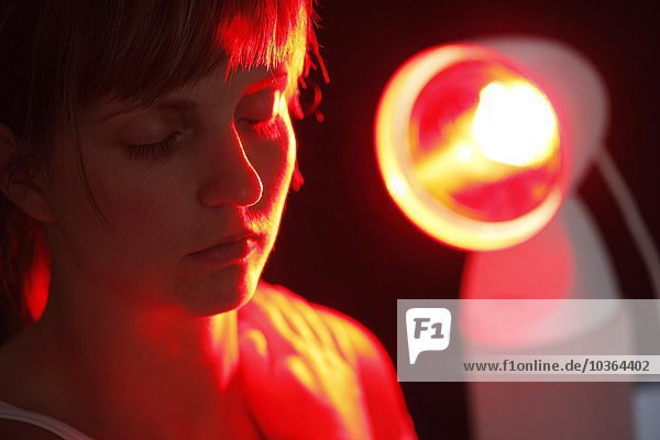 Young adult woman makes be lit up from an ultraviolet hot Lite lamp  against colds  bracings  pains