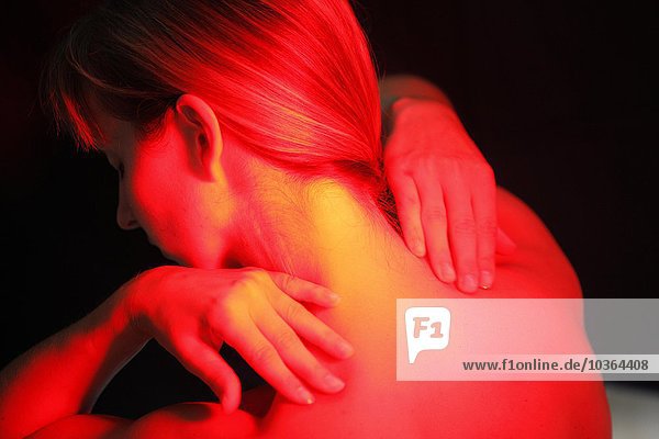 Junge erwachsene Frau lässt sich gegen Erkältungen  Verstauchungen  Schmerzen  von einer ultravioletten heißen Lite-Lampe anstrahlen