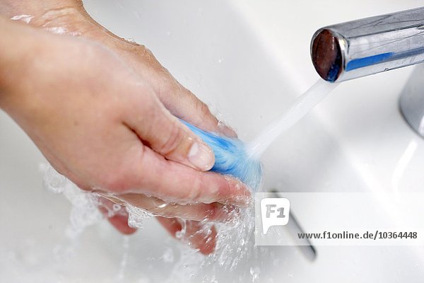 Die Hände werden in einem Handwaschbecken mit Wasser und Seife gewaschen  aus einem Flüssigseifenspender