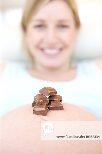 Schokolade auf dem Unterleib einer schwangeren Frau