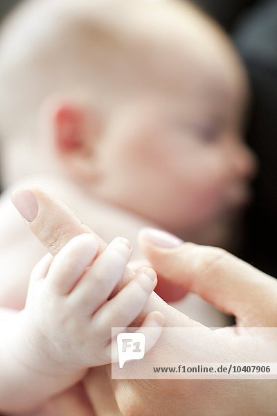 Baby greift nach dem Finger der Mutter