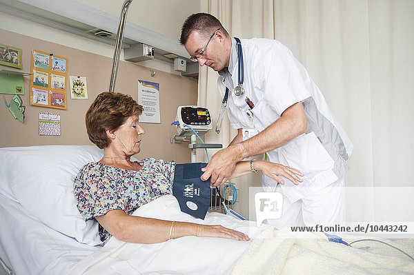 MODELL FREIGEGEBEN. Blutdruckmessung. Krankenschwester misst den Blutdruck eines Patienten Blutdruckmessung