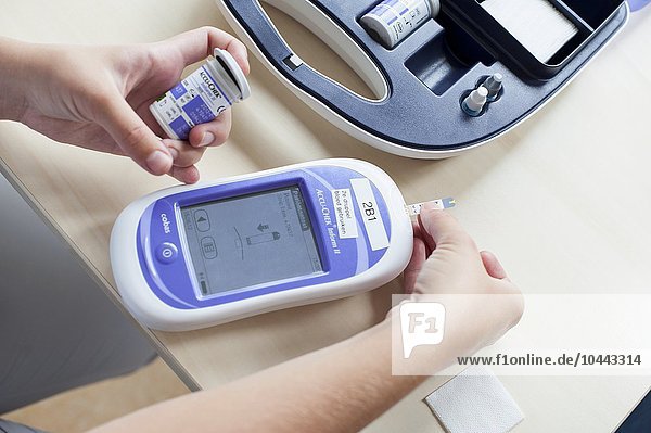MODEL RELEASED. Blood glucose meter. Nurse using a blood glucose meter. Blood glucose meter