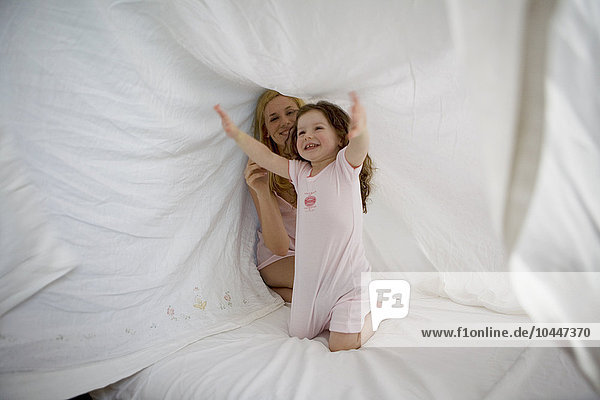 Mutter und Tochter spielen mit Bettlaken