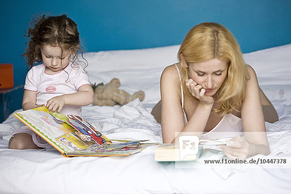 Mutter und Tochter lesen ein Buch auf dem Bett