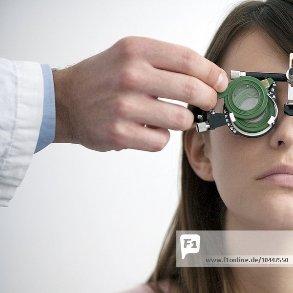 an optician checking a young woman's eyes