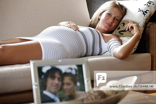 schwangere Frau im Liegen mit Hochzeitsbild auf dem Tisch