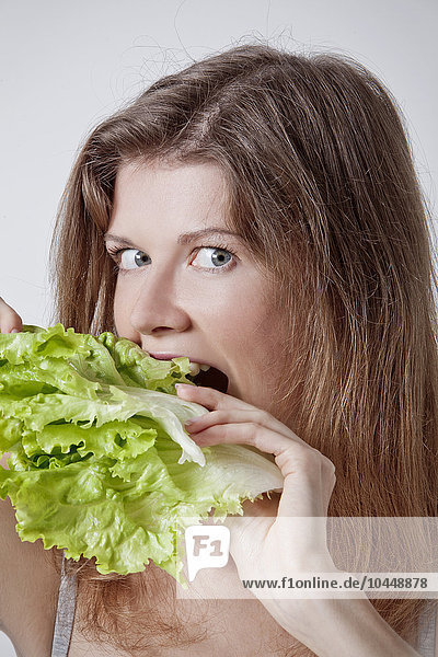 Frau beißt in Salatblätter