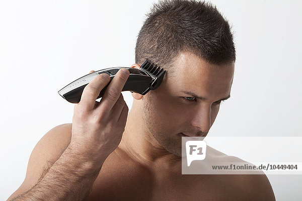 Mann rasiert die Haare mit elektrischem Rasierapparat