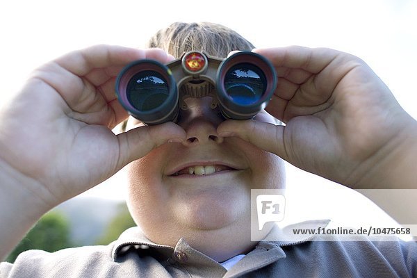 MODEL RELEASED. Boy using binoculars. Boy using binoculars