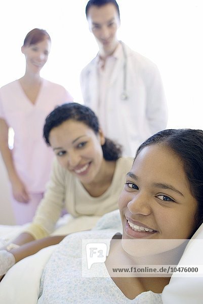 MODELL FREIGEGEBEN. Jugendlicher Patient im Krankenhaus. Teenager-Mädchen mit ihrer Mutter  Arzt und Krankenschwester auf einer Krankenhausstation Teenager-Krankenhaus-Patient
