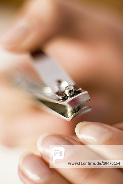 MODEL RELEASED. Cutting nails. Woman cutting her finger nails using a nail clipper. Clipping nails