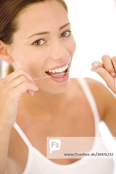 MODELL FREIGEGEBEN. Frau bei der Verwendung von Zahnseide. Mit dieser Reinigungstechnik werden Nahrungspartikel aus den Zahnzwischenräumen entfernt. Frau benutzt Zahnseide