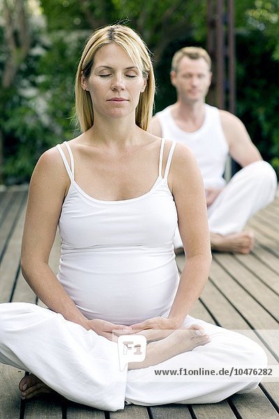MODELL FREIGEGEBEN. Yoga in der Schwangerschaft. Schwangere Frau  die Yoga-Übungen mit ihrem Partner durchführt. Sie befindet sich im dritten Trimester Yoga in der Schwangerschaft