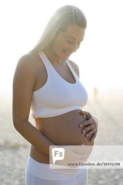 MODELL FREIGEGEBEN. Schwangere Frau blickt auf ihren geschwollenen Bauch Schwangere Frau