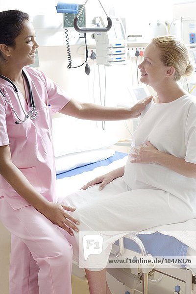 MODELL FREIGEGEBEN. Schwangerschaftsuntersuchung. Gynäkologe im Gespräch mit einer schwangeren Frau auf einer Entbindungsstation Schwangerschaftsuntersuchung