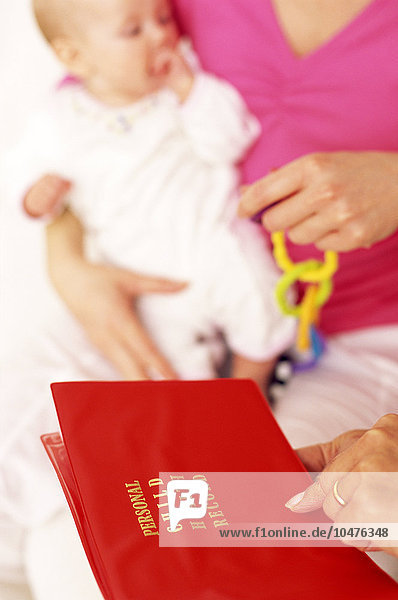 MODELL FREIGEGEBEN. Gesundheitsprotokoll für Babys. Eine Mitarbeiterin des Gesundheitswesens hält ein Buch in der Hand  in dem die körperliche  sensorische und geistige Entwicklung eines Neugeborenen festgehalten wird. Baby Health Record