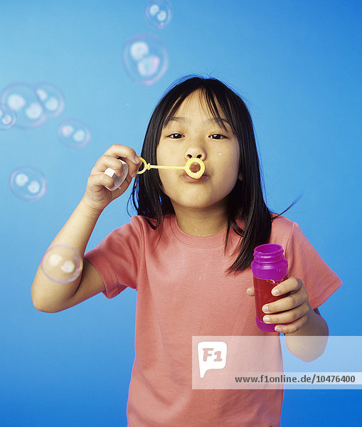 MODELL FREIGEGEBEN. Seifenblasen pusten. 6-jähriges Mädchen bläst Seifenblasen mit einem Zauberstab Seifenblasen