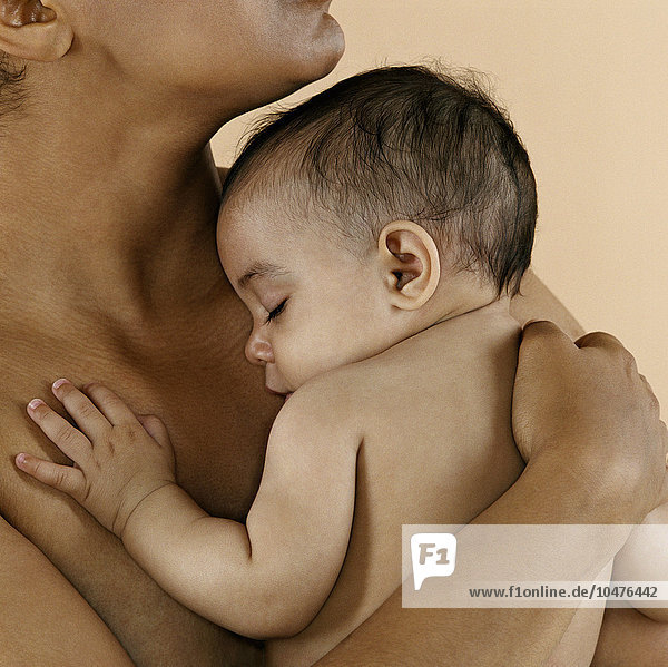 MODEL RELEASED. Baby girl sleeping on her mother's shoulder. She is six months old. Baby girl sleeping
