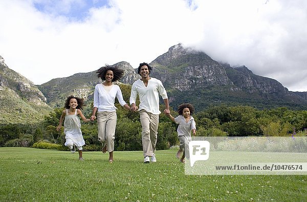 MODEL RELEASED. Happy family. Parents running with their two children in the countryside. Happy family