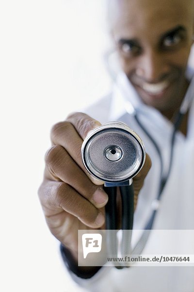 MODELL FREIGEGEBEN. Ein Arzt hält ein Stethoskop. Mit dem Stethoskop kann der Arzt Geräusche im Körper des Patienten abhören. Arzt mit Stethoskop