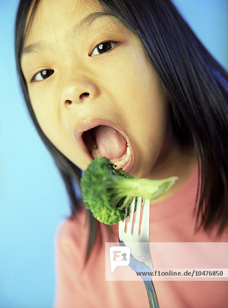 MODELL FREIGEGEBEN. Gesunde Ernährung. Ein 6-jähriges Mädchen isst ihr Grünzeug in Form von Brokkoli (^IBrassica oleracea italica^i). Brokkoli ist eine gute Quelle für Ballaststoffe sowie für die Vitamine A und C.  Gesunde Ernährung