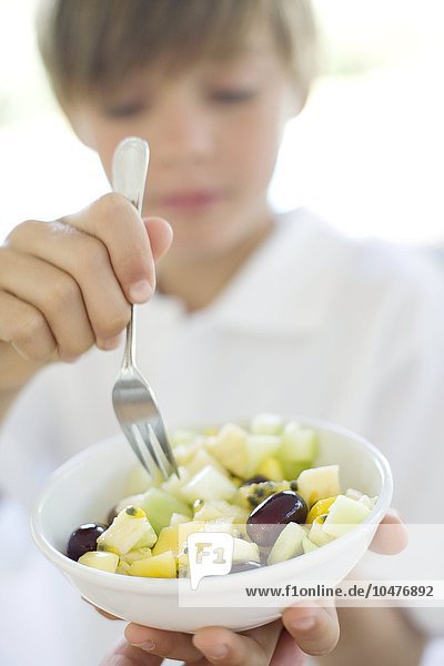 MODEL RELEASED. Healthy eating. 10 year old boy eating a fruit salad. Healthy eating
