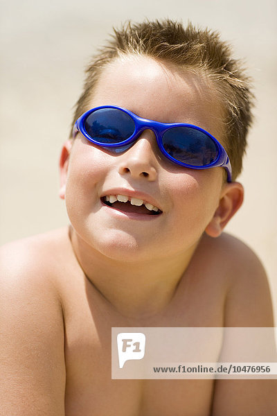 MODEL RELEASED. Boy wearing sunglasses at a beach. Boy wearing sunglasses