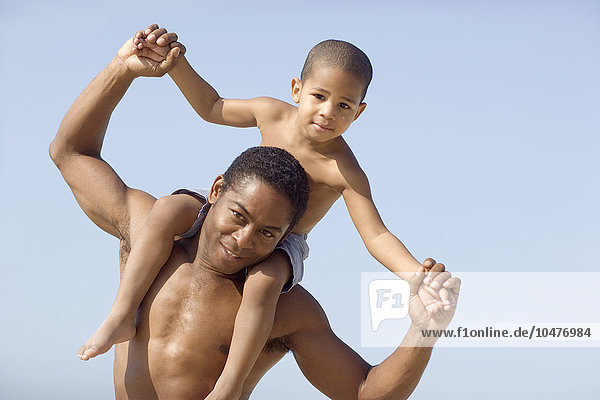 MODELL FREIGEGEBEN. Vater und Sohn. Junge wird auf den Schultern seines Vaters am Strand getragen Vater und Sohn
