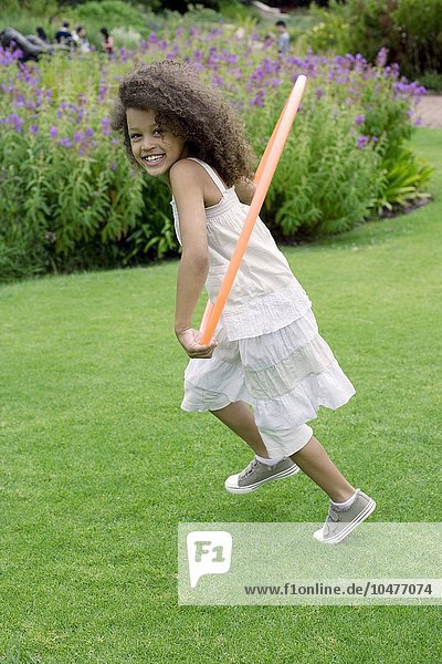 MODEL RELEASED. Girl playing with a hula hoop in a garden. Girl playing with a hula hoop