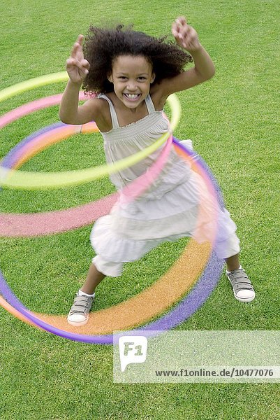 MODELL FREIGEGEBEN. Mädchen spielt mit Hula-Hoop-Reifen in einem Garten Mädchen spielt mit Hula-Hoop-Reifen
