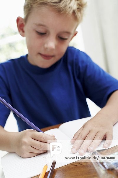Junge zeichnet in ein Schulheft